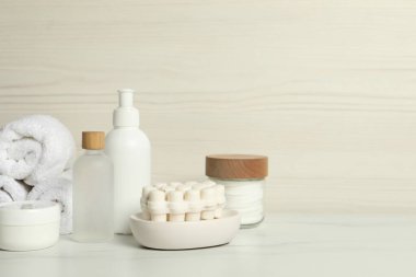 Farklı banyo aksesuarları ve beyaz mermer masa üzerinde kişisel bakım ürünleri, hafif ahşap duvar, metin için yer