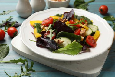 Açık mavi ahşap masada taze vejetaryen salatası, yakın plan.