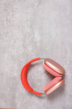 Açık gri masada pembe kulaklıklar, üst manzara. Metin için boşluk