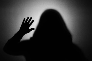 Camın arkasındaki hayalet silueti açık gri arkaplana karşı