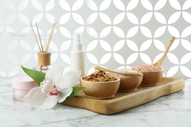 Farklı spa ürünleri ve beyaz mermer masa üzerinde orkide ile güzel bir kompozisyon.