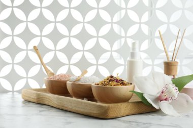 Farklı spa ürünleri ve beyaz mermer masa üzerinde orkide ile güzel bir kompozisyon.