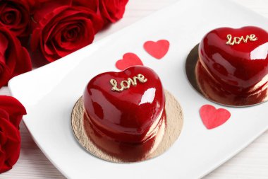 St. Valentine's Day. Delicious heart shaped cakes and roses on table, closeup clipart