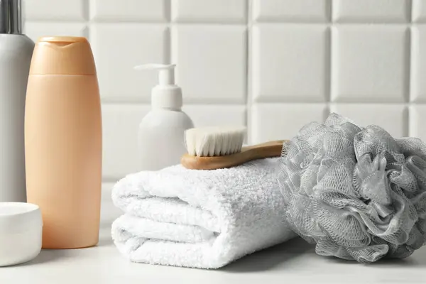 Bath accessories and personal care products on white table near tiled wall, closeup