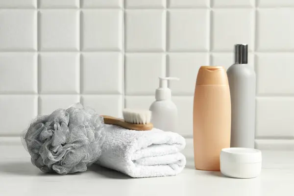 Different bath accessories and personal care products on white table near tiled wall