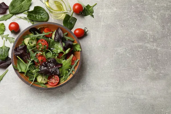 Tasty fresh vegetarian salad and ingredients on grey table, top view. Space for text