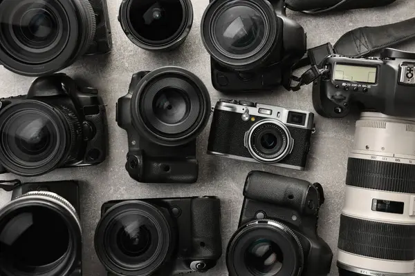 stock image Modern cameras on gray textured table, flat lay