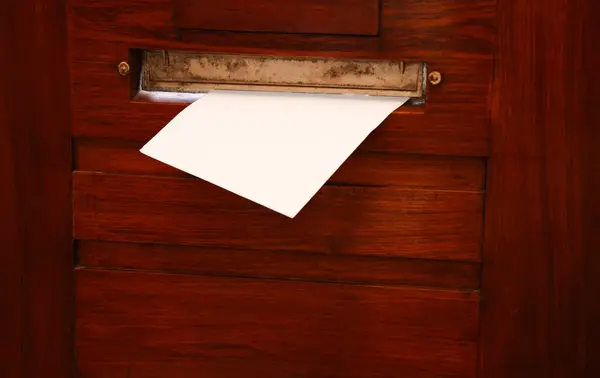Mail slot with envelope in wooden door