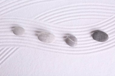 Zen bahçe taşları beyaz kumda desenli, düz yatıyordu.