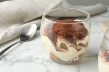 Cam ve kaşıkla nefis tiramisu beyaz mermer masada, yakın plan.