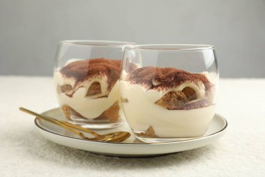Lezzetli tiramisu bardaklar ve kaşıklar beyaz masada, yakın plan.