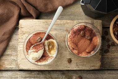 Lezzetli tiramisu bardaklar, kaşık ve kahve çekirdekleri ahşap masa, üst manzara