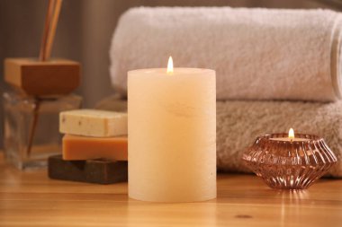 Spa kompozisyonu. Yanan mumlar, havlular, sabun ve kamış oda spreyi ahşap masada, yakın plan.