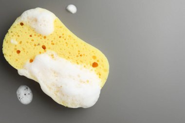 Gri arka planda köpüklü sarı sünger, üst manzara. Metin için boşluk