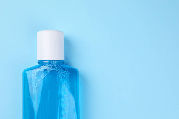 Промывание рта в бутылке на светло-голубом фоне, вид сверху. Пространство для текста