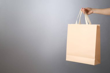 Gri arka planda kağıt poşet tutan kadın, mesaj için yeri olan yakın plan. Tasarım için model