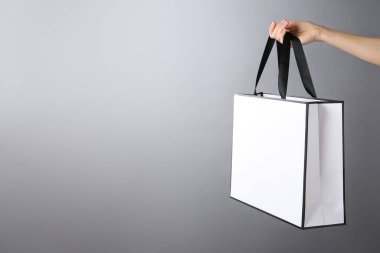 Gri arka planda kağıt poşet tutan kadın, mesaj için yeri olan yakın plan. Tasarım için model