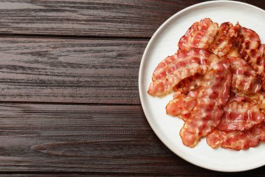 Ahşap masa üzerinde kızarmış pastırma dilimleri ile tabak, üst manzara. Metin için boşluk