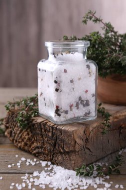 Cam kavanozda biberli tuz ve ahşap masada kekik.