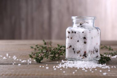 Cam kavanozda biberli tuz ve ahşap masada kekik, metin için boşluk.