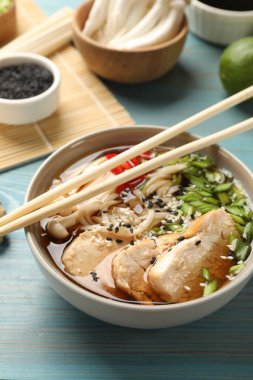 Açık mavi ahşap masada etli ve malzemeli lezzetli ramen. Erişte çorbası.