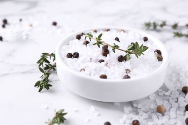 Kekikli tuz ve beyaz mermer masadaki kasede biber, yakın plan.