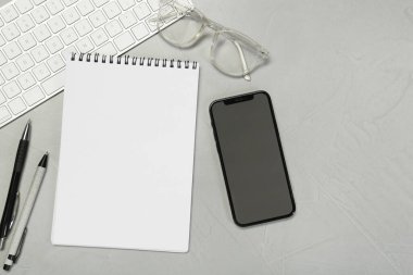 Açık defter ve akıllı telefonla açık gri masada düz kompozisyon
