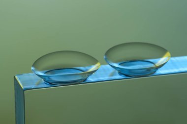 Gri arkaplanla cam üzerine kontak lens, yakın plan.