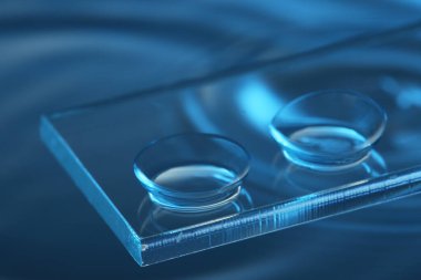 Mavi arkaplanda cam üzerine kontak lens, yakın plan.