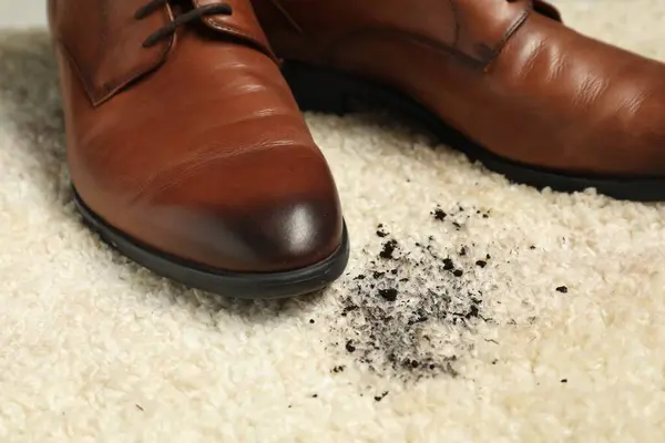 Brown shoes and mud on beige carpet, closeup