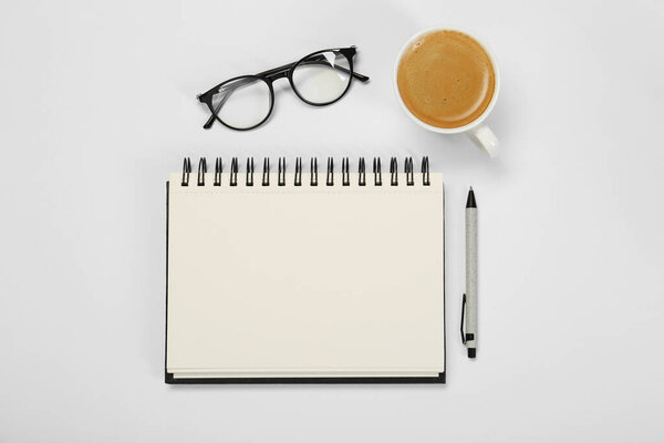Open notebook, coffee, pen and glasses on table, flat lay