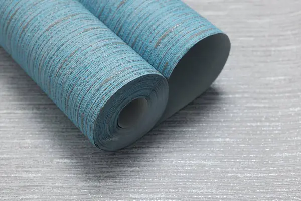 Light blue wallpaper roll on grey sample, space for text