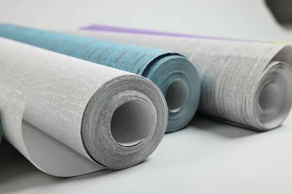 Different stylish wallpaper rolls on white background, closeup