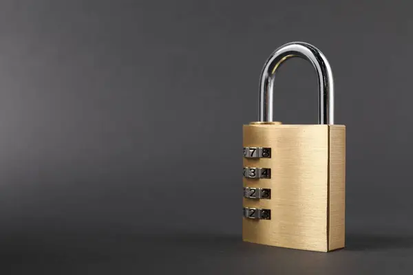 One steel combination padlock on dark grey background, closeup. Space for text