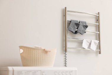 Banyoda beyaz duvarda çorapları olan ısıtmalı havlu rayı.