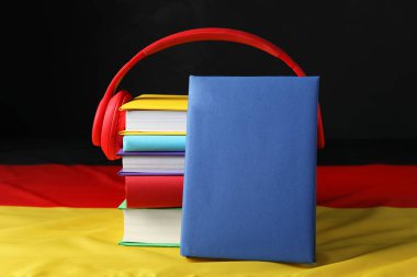 Yabancı dil öğreniyorum. Almanya bayrağında farklı kitaplar ve kulaklıklar