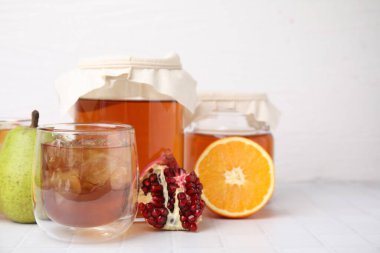 Buz küplü lezzetli kombu çayı ve beyaz fayanslı masada taze meyve, metin için yer var.