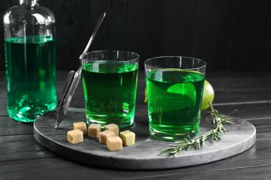 Bardakta absent, biberiye, esmer şeker ve siyah ahşap masada limon. Alkolik içki.