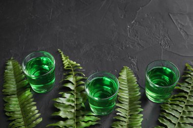 Aspirin bardakları ve yeşil yapraklar siyah masada, mesaj için yer var. Alkolik içki.