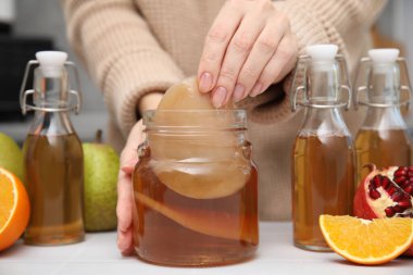 Beyaz masada ev yapımı mayalanmış kombu çayı yapan kadın, yakın plan.