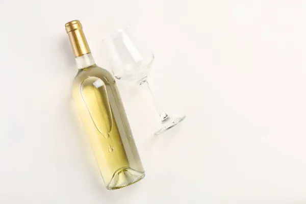 Bottle of expensive white wine and wineglass on light background, top view. Space for text