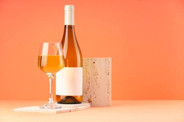 Lezzetli şarabın şişede sunumu ve turuncu arka planda cam. Metin için boşluk