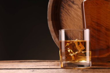Buzlu viski, cam, şişe ve fıçı ile ahşap masa üzerinde siyah arkaplan, metin için yer