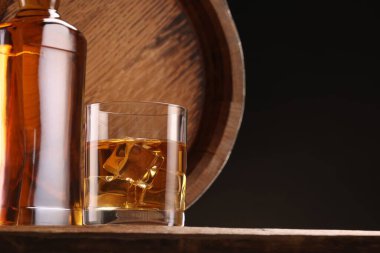 Buzlu viski, cam, şişe ve fıçı ile ahşap masa üzerinde siyah arkaplan, metin için yer