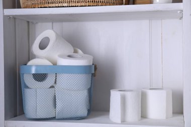 Tuvalet kağıdı beyaz rafta sepette yuvarlanıyor.