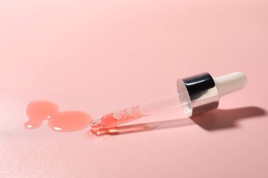 Pembe arka planda boru ve nemlendirici serum.