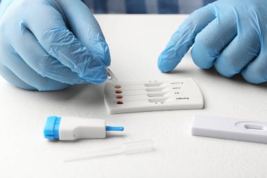 Doktor tek kullanımlık çoklu enfeksiyonlu ekspres test kasetine tampon çözeltisi bırakıyor.