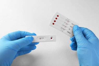 Doktor beyaz masada iki adet kullan-at test tutuyor, yakın plan.