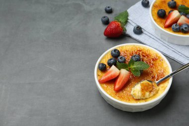 Lezzetli creme brulee kasede böğürtlen ve gri masada kaşık. Metin için boşluk