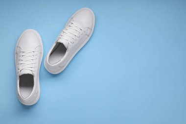 Açık mavi arka planda bir çift şık beyaz spor ayakkabı, üst manzara. Metin için boşluk